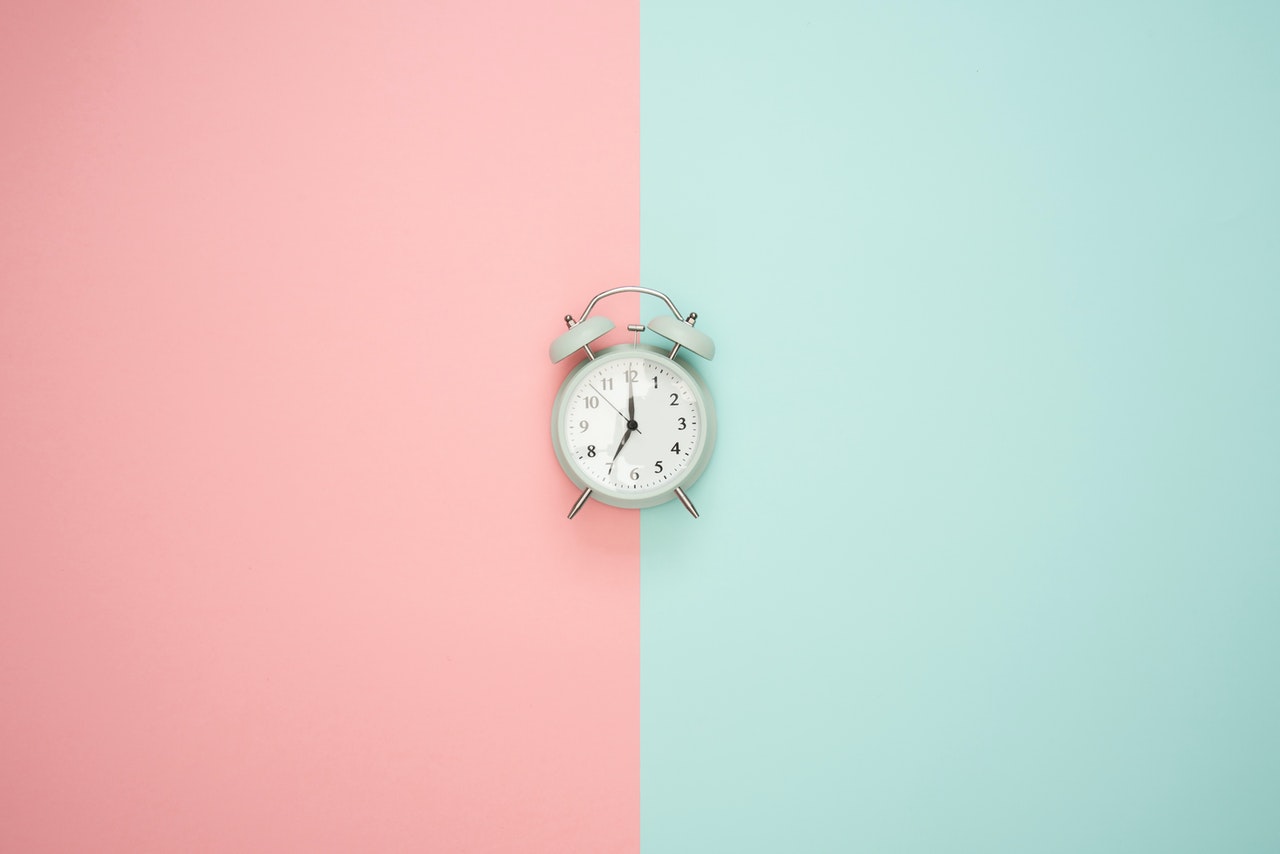 A clock on a pink & blue background.