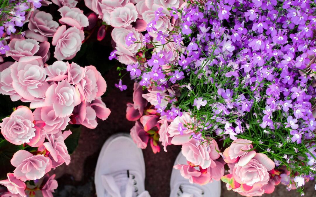 A person’s feet surrounded by colorful flowers.